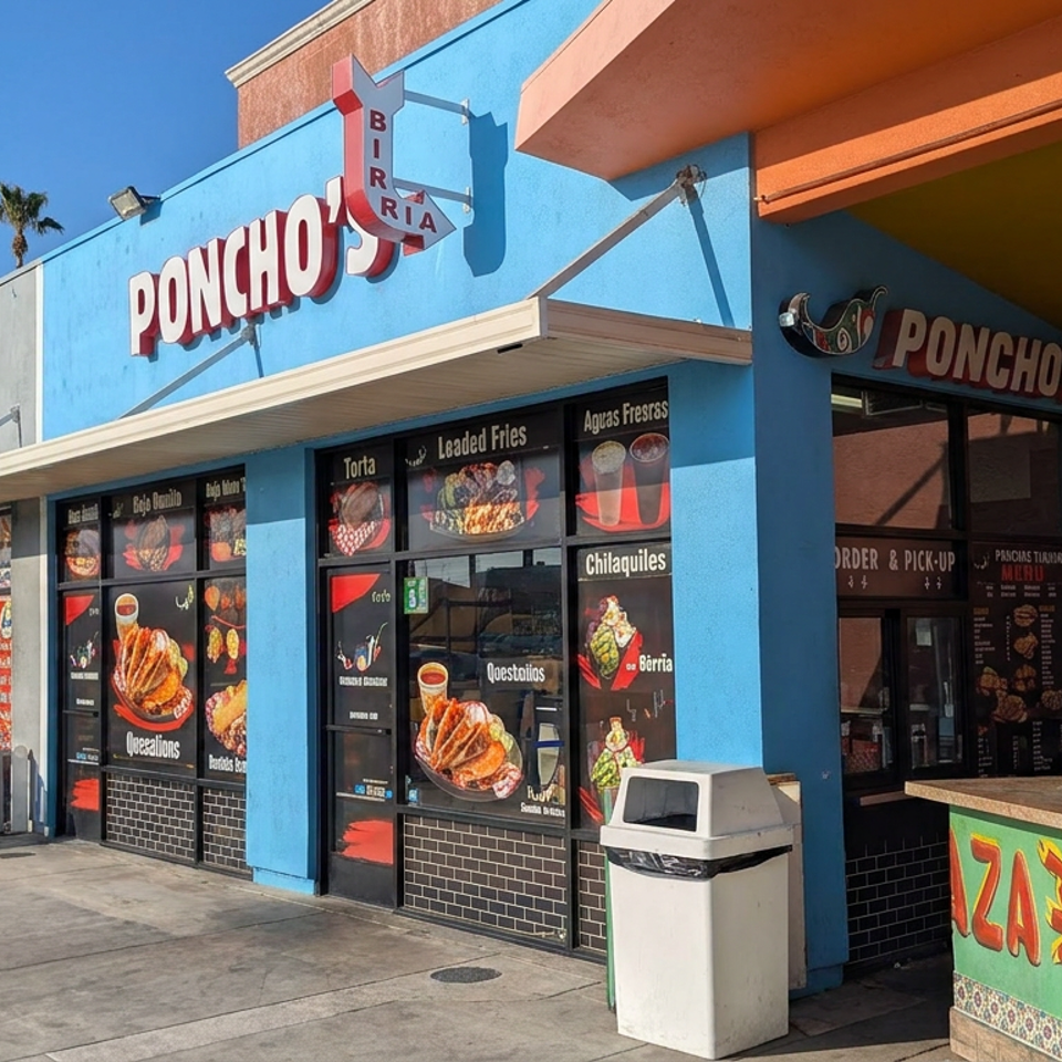 Brightly painted Poncho’s Birria restaurant exterior displays Mexican food photos, with two people dining at an outdoor counter.